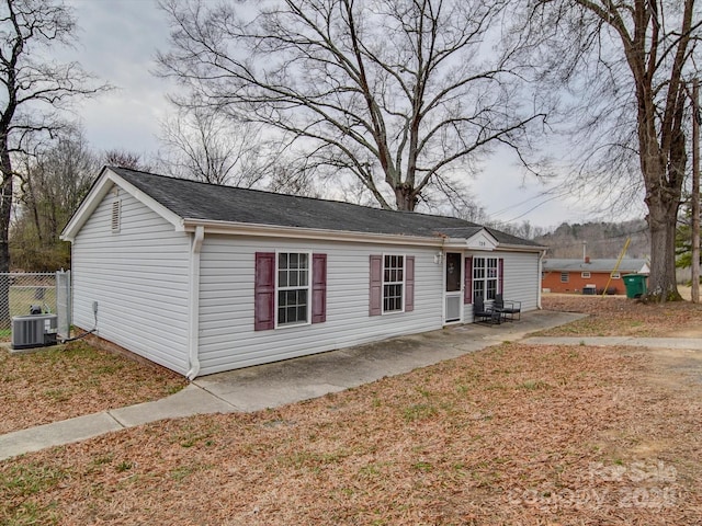 view of front of home with central AC, a patio, and fence