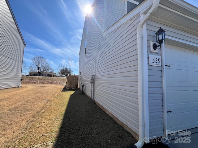 view of home's exterior featuring an attached garage and fence