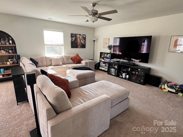 living area featuring light carpet, visible vents, and a ceiling fan