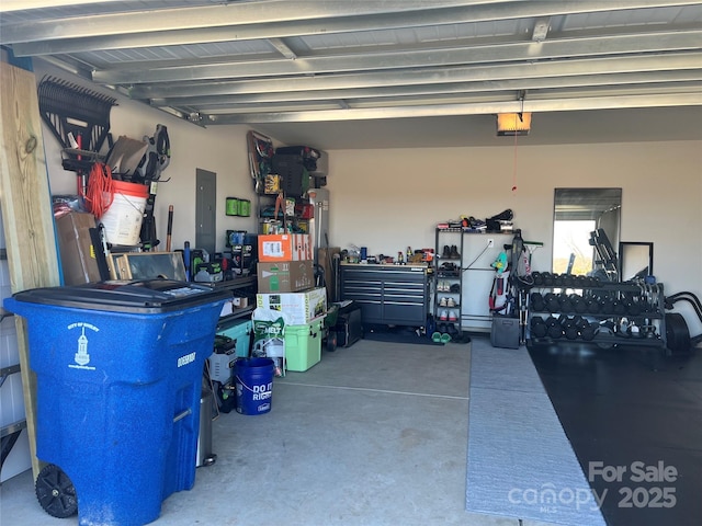 garage featuring a garage door opener, electric panel, and a workshop area