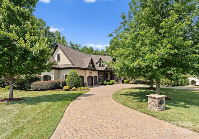 view of front of home with stone siding, decorative driveway, a front lawn, and stucco siding