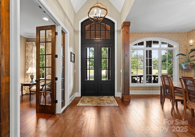 entryway featuring wallpapered walls, baseboards, wood finished floors, french doors, and a notable chandelier