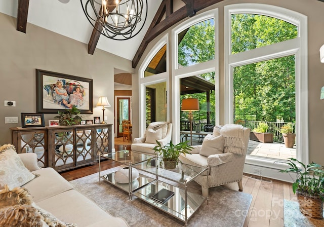 living room with visible vents, wood finished floors, beamed ceiling, high vaulted ceiling, and a notable chandelier