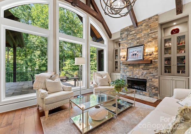 living area with built in features, a fireplace, light wood finished floors, visible vents, and beamed ceiling