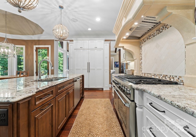 kitchen featuring stainless steel appliances, hanging light fixtures, white cabinetry, a sink, and a chandelier