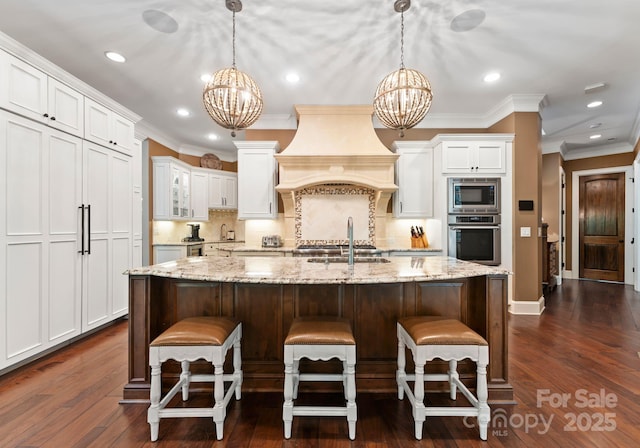 kitchen featuring premium range hood, appliances with stainless steel finishes, decorative light fixtures, and a notable chandelier