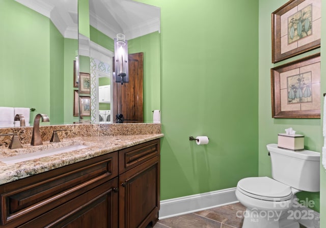 bathroom with crown molding, toilet, vanity, and baseboards