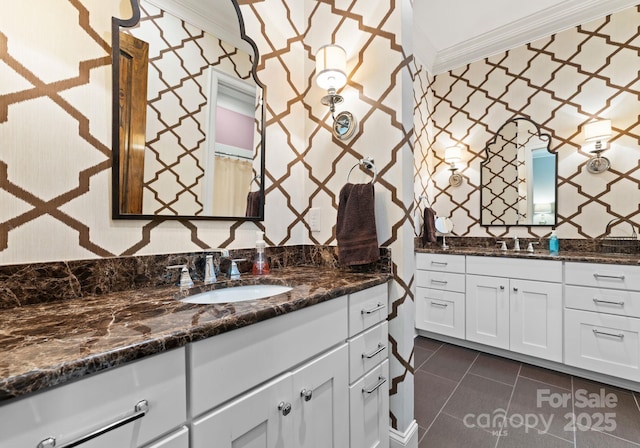 bathroom with tile patterned flooring, ornamental molding, two vanities, and a sink