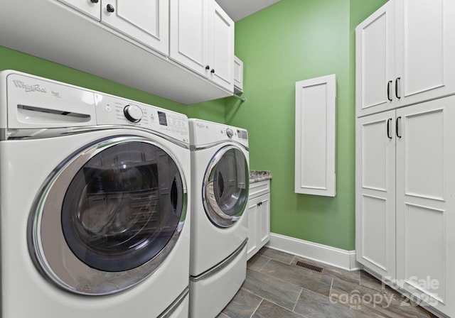 washroom with visible vents, baseboards, cabinet space, and washer and dryer