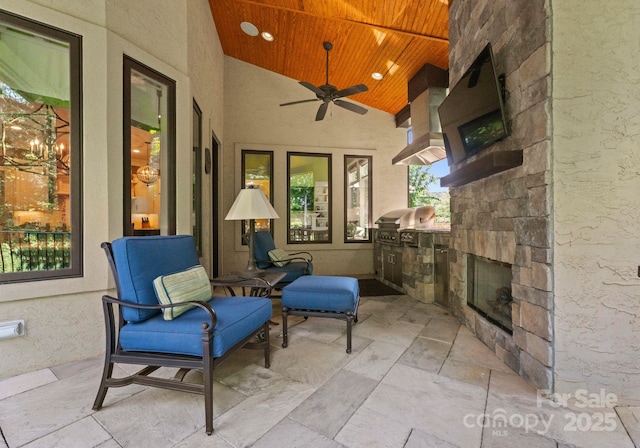 view of patio with ceiling fan, an outdoor stone fireplace, and an outdoor kitchen