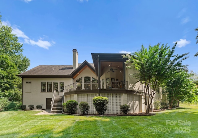 rear view of property featuring stairs, a yard, a ceiling fan, and stucco siding