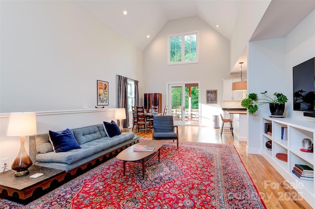 living room featuring plenty of natural light, high vaulted ceiling, and light wood-type flooring