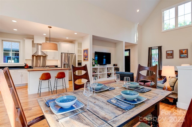 dining room with high vaulted ceiling, light wood finished floors, and recessed lighting