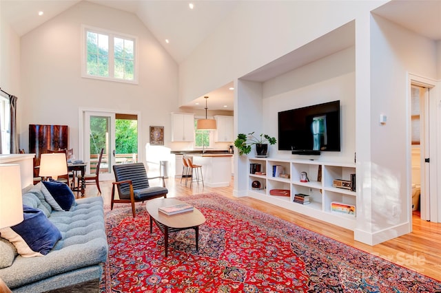 living area with baseboards, high vaulted ceiling, wood finished floors, and recessed lighting