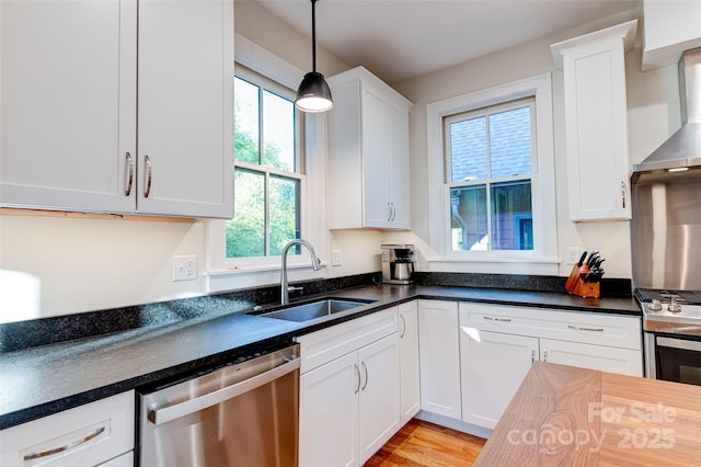 kitchen with stainless steel appliances, dark countertops, a sink, and white cabinets