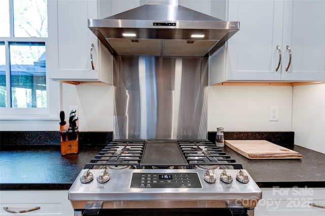 kitchen with dark countertops, gas range, and white cabinetry