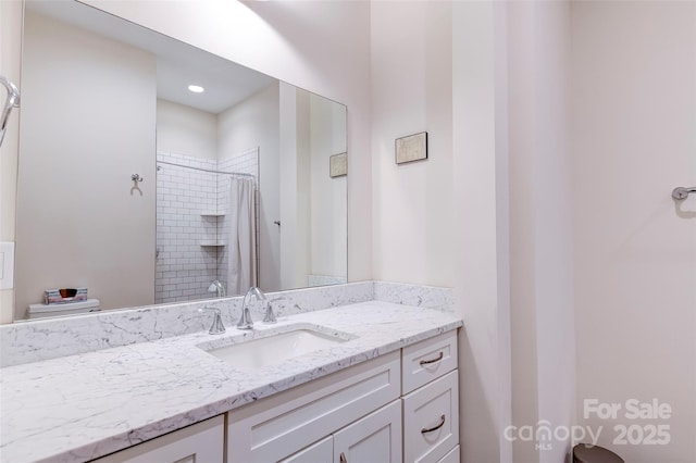 bathroom with tiled shower and vanity