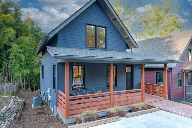 view of front of property with covered porch, central AC, and roof with shingles