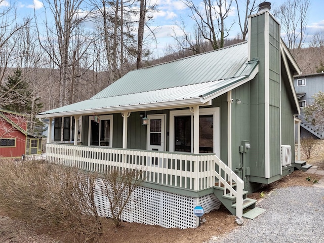 view of front of house featuring ac unit, metal roof, a porch, and a chimney