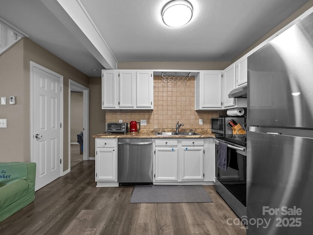 kitchen with a sink, stainless steel appliances, under cabinet range hood, and white cabinetry