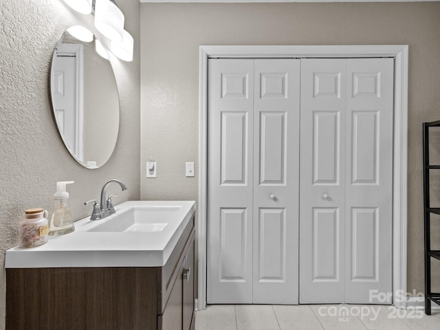 bathroom featuring a closet, tile patterned floors, vanity, and a textured wall