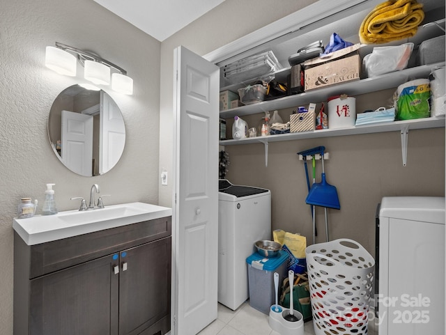 laundry area with light tile patterned flooring, washer / dryer, and a sink