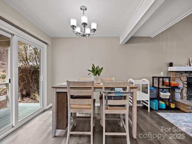 dining space with a fireplace, wood finished floors, a notable chandelier, and a healthy amount of sunlight