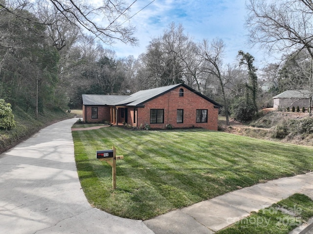 view of front of home featuring a front yard, brick siding, and driveway