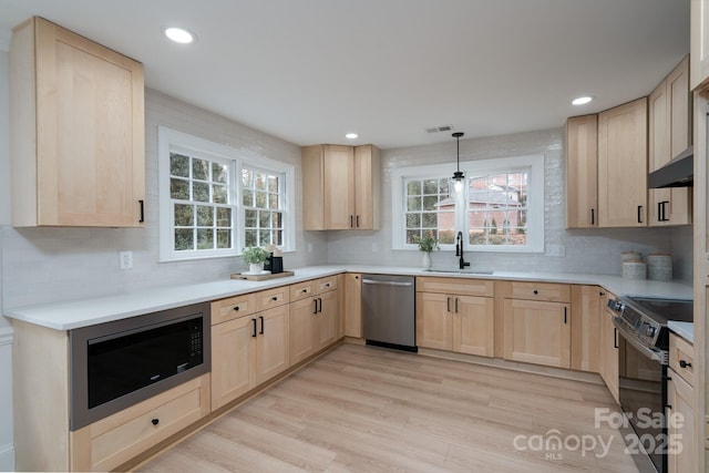 kitchen featuring black electric range oven, built in microwave, stainless steel dishwasher, light brown cabinets, and a sink