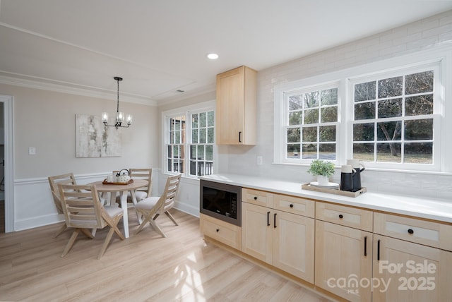 kitchen featuring light countertops, light wood-type flooring, built in microwave, light brown cabinetry, and crown molding