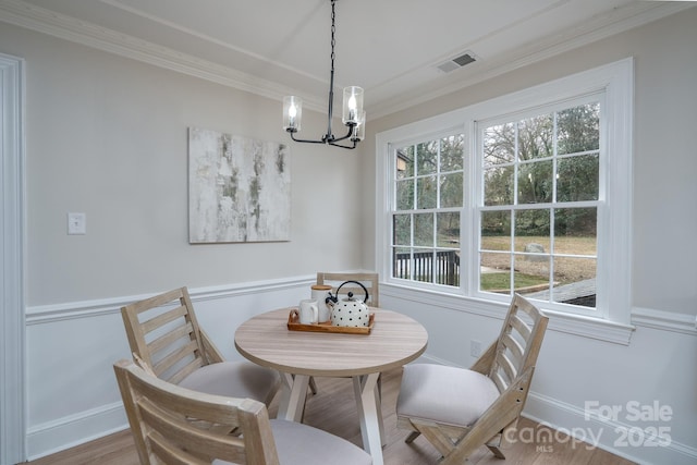 dining space with ornamental molding, visible vents, plenty of natural light, and wood finished floors