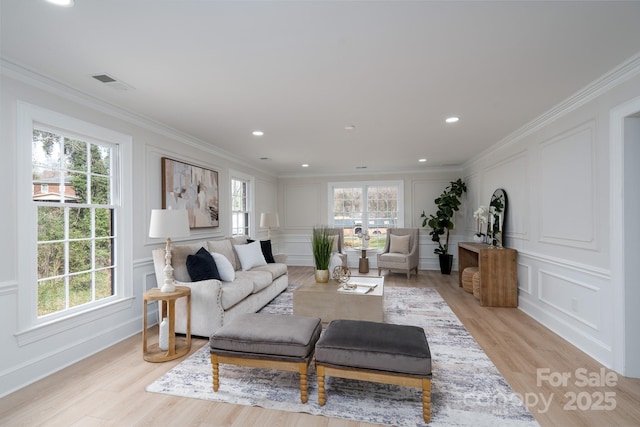 living area with ornamental molding, a healthy amount of sunlight, visible vents, and a decorative wall