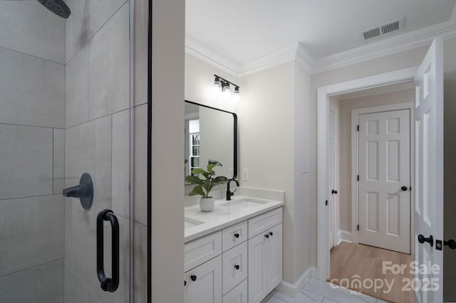 full bath featuring double vanity, visible vents, ornamental molding, a sink, and tiled shower