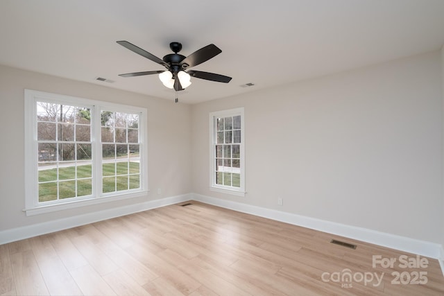 unfurnished room with ceiling fan, light wood finished floors, visible vents, and baseboards