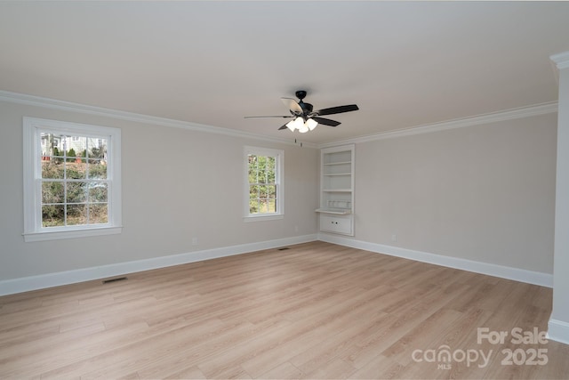 empty room with crown molding, light wood-style flooring, and baseboards