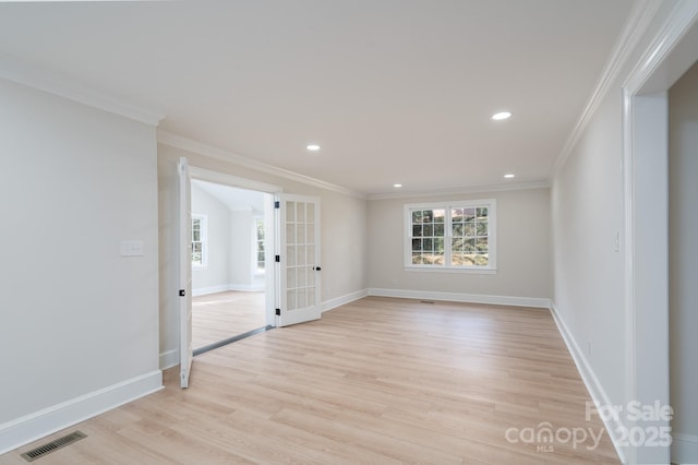 empty room with light wood-type flooring, plenty of natural light, visible vents, and ornamental molding