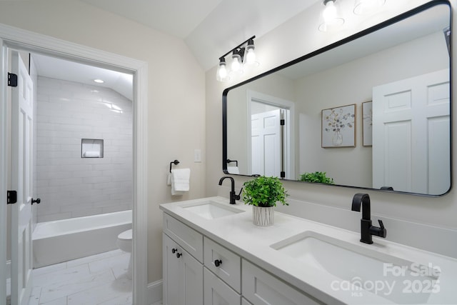 bathroom with toilet, marble finish floor, double vanity, and a sink