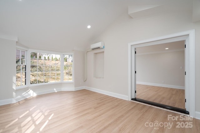 empty room featuring a wall mounted air conditioner, baseboards, and wood finished floors