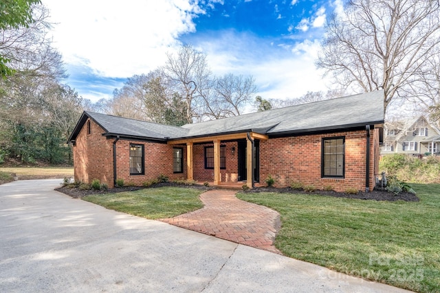 view of front of property featuring a front yard, covered porch, and brick siding