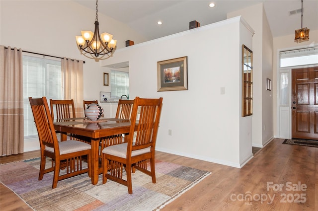 dining area featuring baseboards, visible vents, a chandelier, and wood finished floors