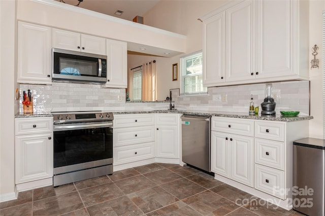 kitchen with stainless steel appliances, light stone countertops, and white cabinets