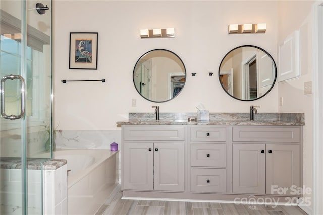 full bath with a garden tub, a sink, a shower stall, and double vanity