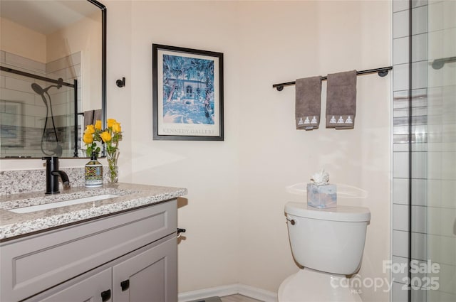 full bath with a tile shower, vanity, toilet, and baseboards