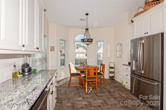 kitchen featuring visible vents, white cabinetry, backsplash, light stone countertops, and stainless steel fridge