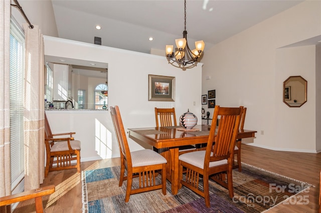 dining space featuring lofted ceiling, recessed lighting, a notable chandelier, wood finished floors, and baseboards