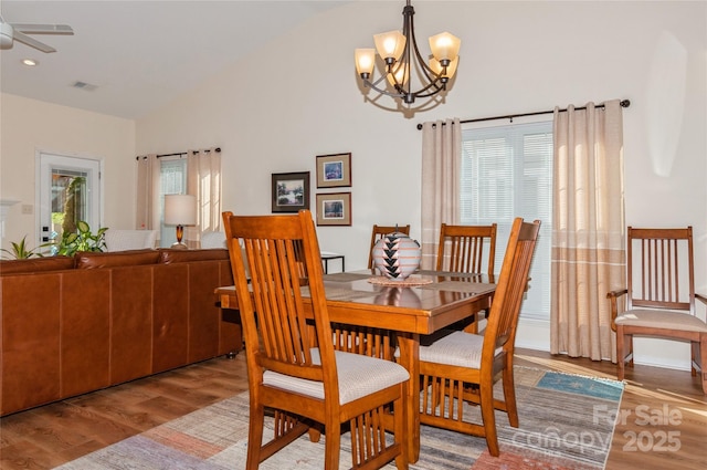 dining space featuring light wood-type flooring, a healthy amount of sunlight, visible vents, and ceiling fan with notable chandelier