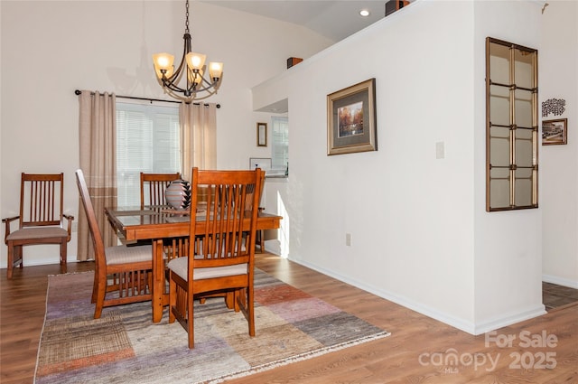 dining area featuring lofted ceiling, an inviting chandelier, and wood finished floors