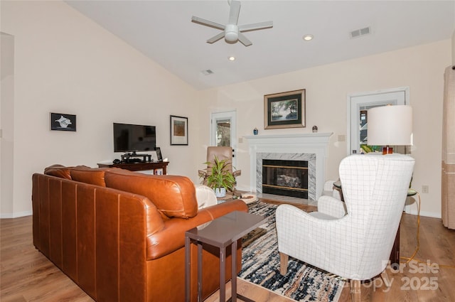 living area with lofted ceiling, ceiling fan, light wood-type flooring, a fireplace, and recessed lighting