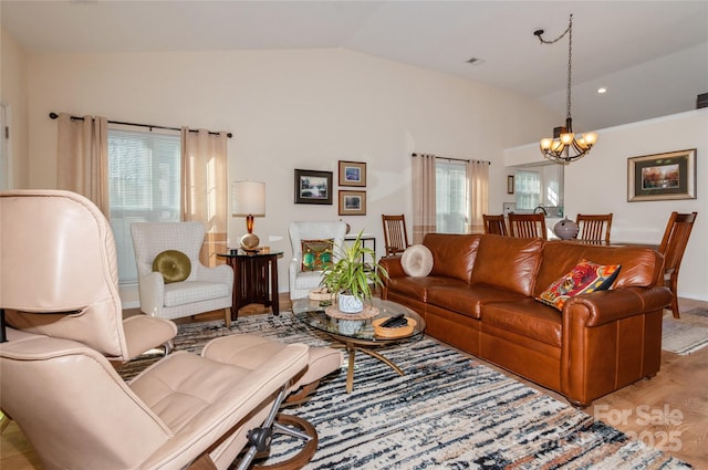 living room with light wood-type flooring, a chandelier, and vaulted ceiling