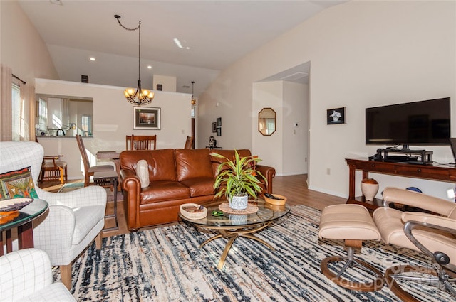 living room featuring vaulted ceiling, wood finished floors, and a notable chandelier